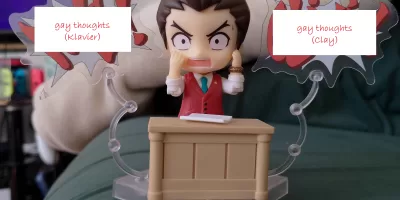 Apollo Justice Ace Attorney in Nendoroid form wrestles with his gay thoughts in the form of badly-photoshopped speech bubbles shouting out his barely-subtextual homoerotic feelings about Clay and Klavier. There's also a fetching cameo from Rebecca's ancient (but sooo comfy) green sofa.